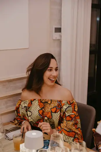 Géraldine, souriante, assise à une table dressée